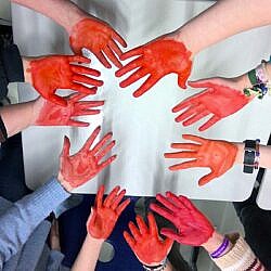 Für den Handabdruck haben sich die ProjektteilnehmerInnen ihre Hände mit Wasserfabe rot angemalt. © GFS